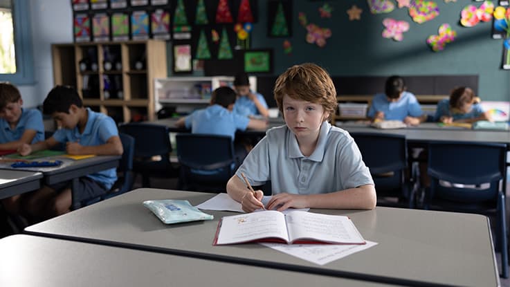 Boy sitting in classroom using a workbook