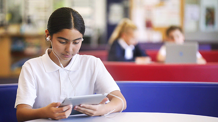 girl using an iPad in a school library 